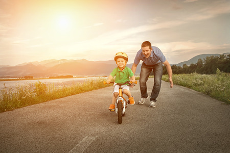 Glücklicher Vater mit Sohn auf dem Fahrrad im Freien